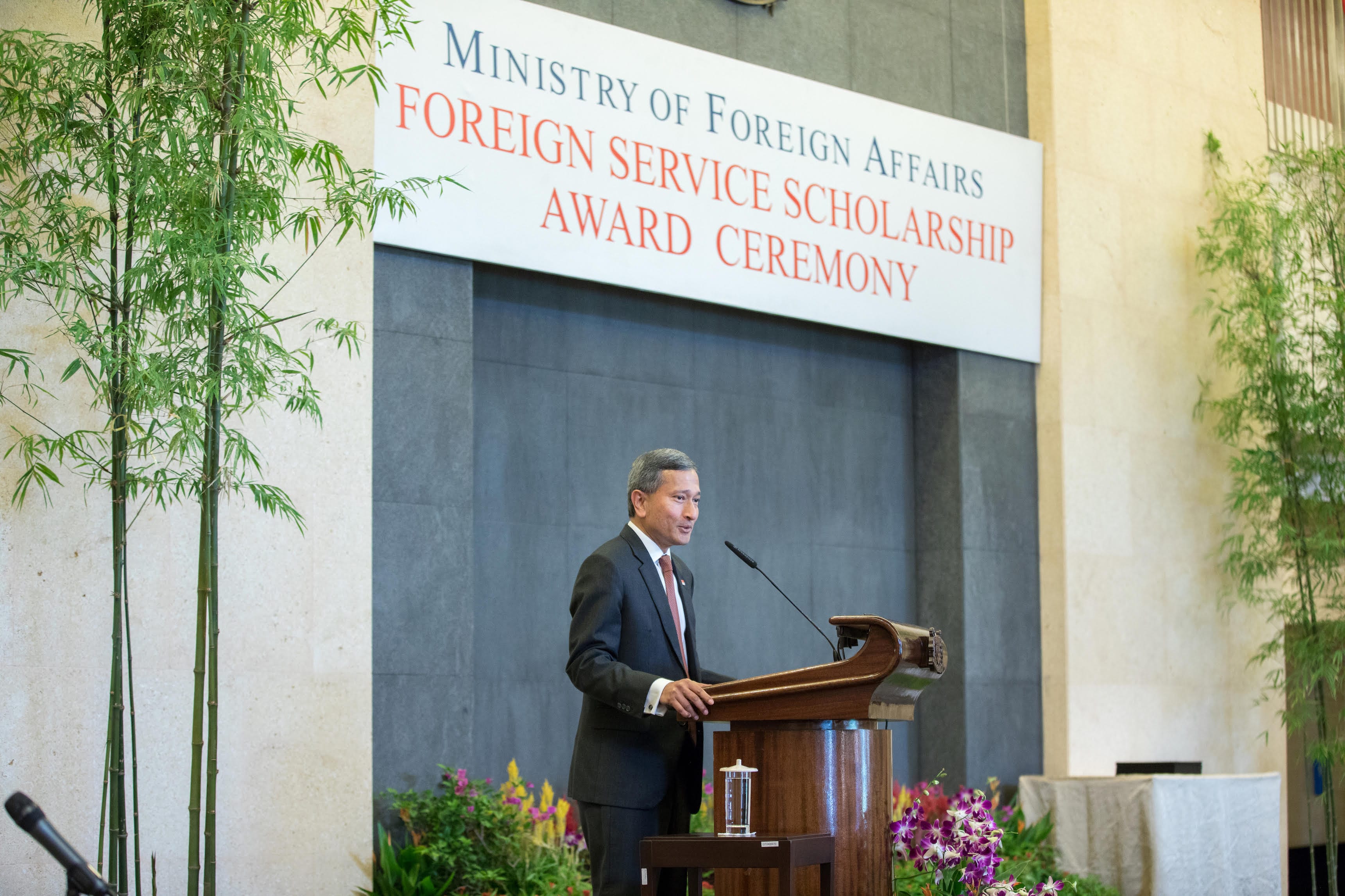 People in business attire sit at a set table with water bottles and menus.